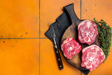 Raw lamb neck chops, fresh mutton meat on a butcher board with herbs. Orange background. Top view....