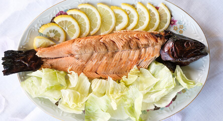 smoked trout on a plate with lemon slices and coleslaw
