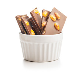 Broken chocolate bar with almonds in bowl isolated on white background.