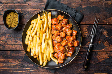 German currywurst meal, curry wurst with french fry served in a plate. Wooden background. Top view