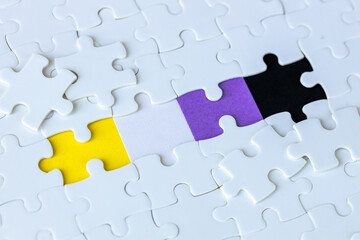 scattered white puzzles from under which emerges the symbol of non-binary people, the concept of gender identity and fluidity
