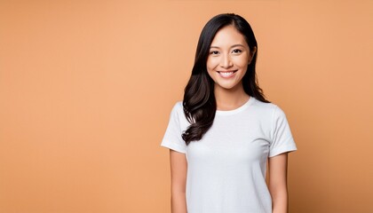 Portrait of a smilling asian woman wearing a white t-shirt and jeans,isolated on solid peach color background