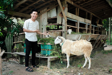 Muslim man standing showing his goat at goat farm. eid al adha concept