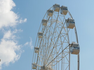 Ferris wheel against a background of blue sky and white cloud.