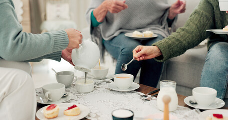 Hands, tea party and senior friends in the living room of their home together for a visit during...