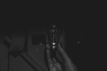 An incandescent lamp in the hands of a girl in the corridor near the meter, black and white photo, without light