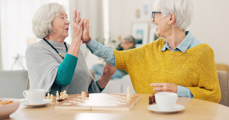 Senior woman, friends and high five for chess match, game or winning on table together at home....