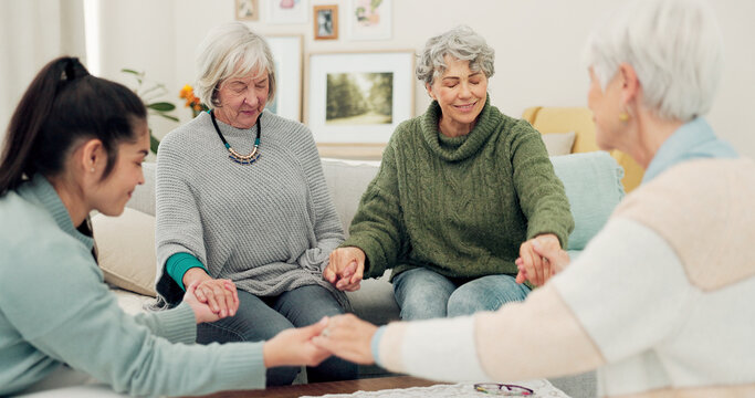 Senior group, holding hands and pray in elderly care for support, trust or unity in social gathering at home. Mature women touching in team activity, share or praying for hope in retirement together