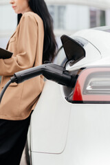 Close-up female hands unplug charger plug from charging station to his electric car before driving...