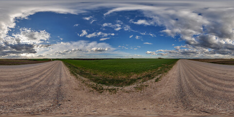 hdri 360 panorama on wet gravel road among fields in spring nasty day with storm clouds before sunset in equirectangular full seamless spherical projection, for VR AR virtual reality content