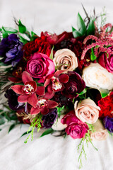 A beautiful wedding bouquet with red, pink, and cream roses and green leaves