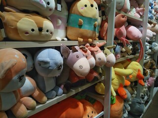 Cute animal dolls on orderly shelf in gift shop-toy store background