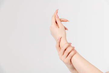 Close-up view of caucasian woman rubbing her wrist using other hand against grey background. Soft...