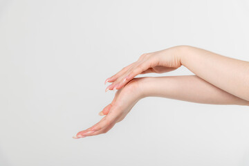 Close-up side view of elegant female hands touching each other during dance against grey...