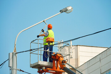 Utility worker paint street light pole, painting lamppost with brush. Painter in lift bucket paint...