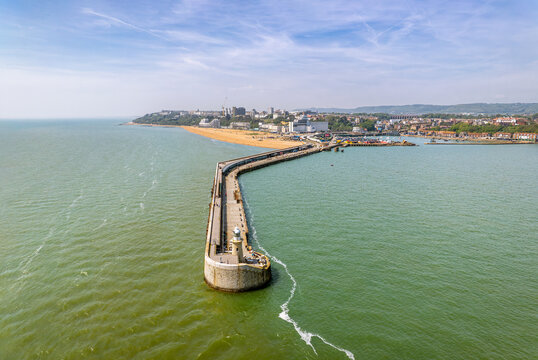 The drone aerial view of Folkestone Harbour Arm and Folkestone city, England. Folkestone's restored Harbour Arm is a beautiful promenade out at sea with a World-class view.