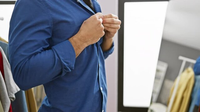 Handsome man dressing in a stylish blue shirt in a modern wardrobe room
