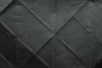 A sheet of folded black color paper texture as background