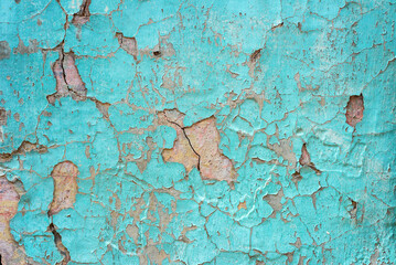 Old weathered concrete wall with peeling paint with bright blue colors on each layer textured...