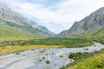 Mountain river of the village of Dargavs. Beautiful panorama of green alpine meadows, hills and...