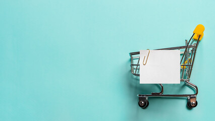 Shopping cart and white paper note list on blue © fascinadora