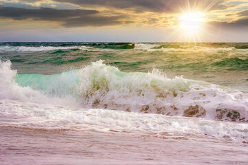 seascape with waves crashing the beach at sunset. beautiful summer scenery at the sea in evening light