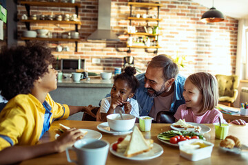 Joyful family breakfast with father and children in home kitchen