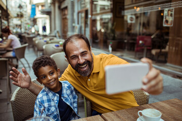 Father and son taking selfie at outdoor cafe
