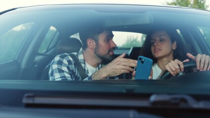 Young couple arguing while driving a car, using navigation on phone Slow motion