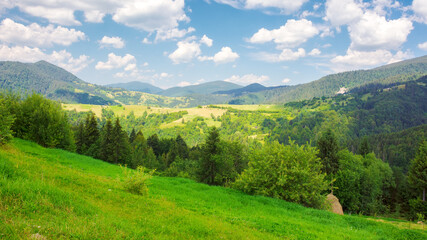 nature scenery with hills and meadows. rural valley in the distance. sunny afternoon in summer. beautiful countryside landscape of ukrainian carpathians in dappled light beneath a sky with clouds