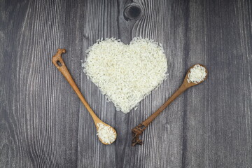 Heart-shaped rice on dark background. Love and valentines day concept. Raw long white rice in shape of heart. Traditional Asian food.