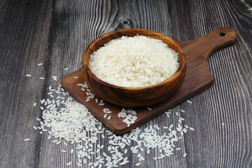 Raw white rice on wooden background. Long uncooked rice in wooden plate. Natural organic food....