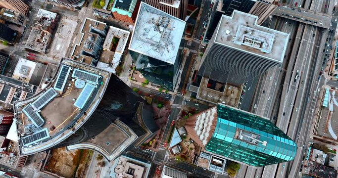 Diversely shaped roof tops of the high-rise buildings and skyscrapers in the downtown of Seattle, Washington State, the USA. Multiple cars move by the roads and streets of the city.