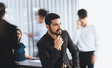 Businessman portrait poses confidently with diverse coworkers in busy meeting room in motion...