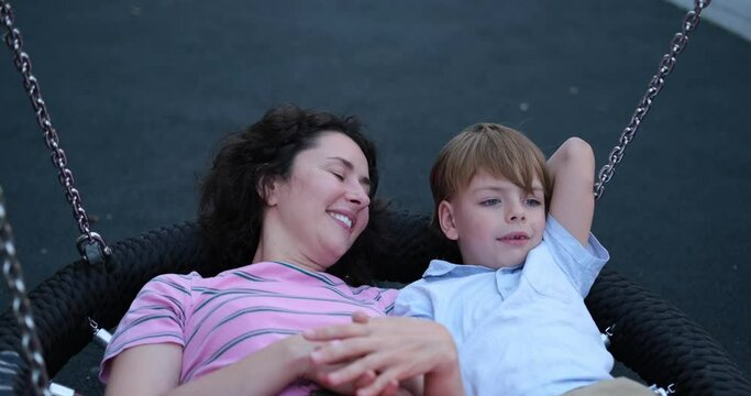 Family day or spending time together concept. Cute caucasian brunette mother having fun with her kid son oa a playground. Outdoor activities