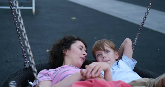 Cute caucasian brunette mother having fun with her kid son oa a playground. Outdoor activities. Family day or spending time together concept