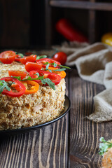 Close-up of a savory pie topped with fresh tomatoes and arugula on a wooden background.