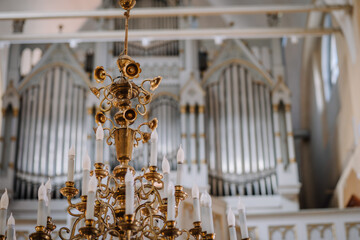 Valmiera, Latvia - May 12, 2024 - a grand golden chandelier with candles in front of church organ...