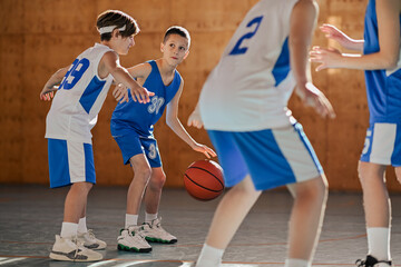 Junior basketball team in action practicing game playing at court.