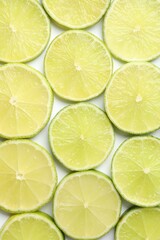 Fresh juicy lime slices on white background, flat lay