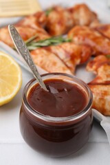 Fresh marinade with spoon in jar on light tiled table, closeup