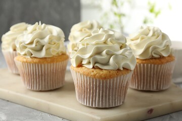 Tasty cupcakes with vanilla cream on grey table, closeup