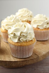 Tasty cupcakes with vanilla cream on pink wooden table, closeup