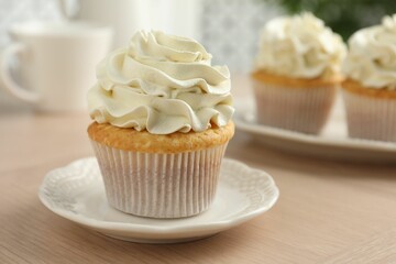 Tasty cupcake with vanilla cream on light wooden table, closeup