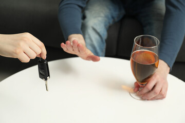 Man with glass of alcoholic drink refusing drive car while woman suggesting him keys, closeup....
