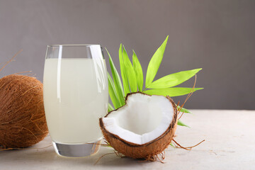 Glass of coconut water, palm leaves and nuts on light table