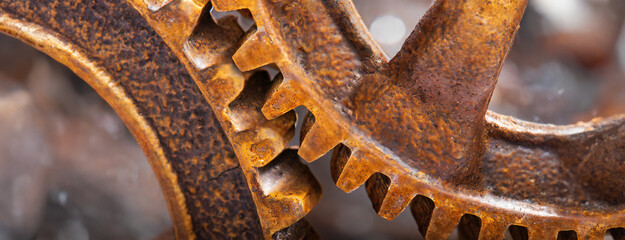 Detailed view of two interlocking rusty gears highlighting their aged and textured surfaces. Show wear and oxidation, beauty of industrial decay and history. Panorama with copy space.