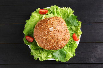 Tasty vegetarian burger on black wooden table, top view