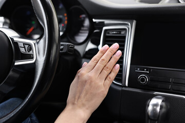 Woman checking air conditioner in her car, closeup