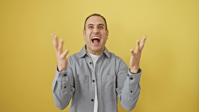 Young hispanic guy in shirt, ecstatically celebrates his vibrant win! arms raised, yes-faced on yellow, expressing pure joyous triumph. victory never looked this good.
